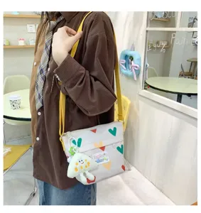 Canvas crossbody bag detail showing colorful heart patterns and cute plush mushroom keychain.