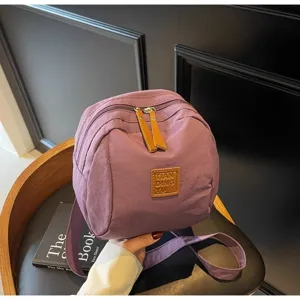 Gros plan détaillé du sac à main violet en nylon avec des tirettes en cuir marron.