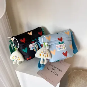 Canvas crossbody shoulder bag with colorful heart print and cute plush pendant for daily use.