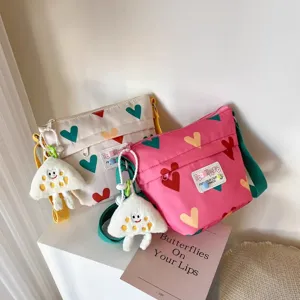 Cute canvas shoulder bag detail featuring colorful heart prints and adorable plush toy charms.