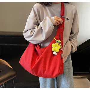 Vue détaillée d'un sac bandoulière rouge en toile décontracté avec un pendentif fleur jaune.
