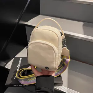 Bolso cruzado mini beige compacto con dobles bolsillos delanteros y correa colorida.