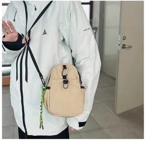 Detail view of a lightweight casual beige mini crossbody bag with carabiner and keychain.