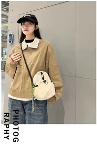 Detailed view of lightweight canvas crossbody sling bag casual daily wear in neutral white tone.
