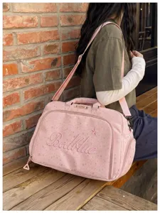 Pink travel duffel bag with star print and shoulder strap, lifestyle scene detail view.