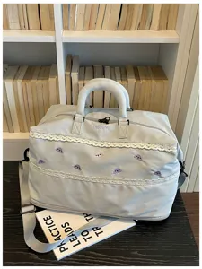 Detail view of large grey travel duffel bag with cute purple cloud embroidery and lace trim.