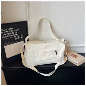 Détail de sac de voyage de sport en toile blanche, sac bandoulière fitness avec poche avant.