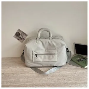 Detail shot of light grey travel duffel bag with front zipper pocket and shoulder strap.
