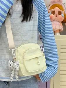 Close-up of a cute yellow canvas crossbody bag with multi pockets and a sweet bow charm.