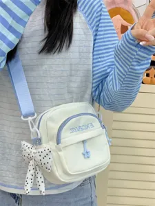Canvas crossbody bag detail view with sweet bow pendant, multi-pocket design, light blue strap.