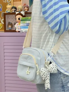Casual light blue canvas crossbody bag with cute star zipper pulls and polka dot bow accessory.