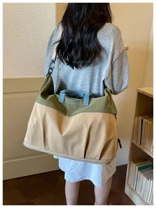 Vista detallada de bolsa de viaje grande con diseño bicolor y correa para el hombro.