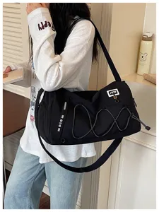 Detail view of black travel duffel gym bag with elastic cord and shoulder strap design.