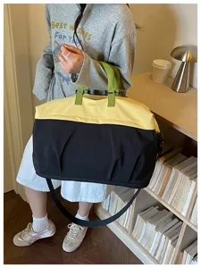 Gran bolsa de viaje duffel tipo color-block con asas verdes y correa para hombro práctica.