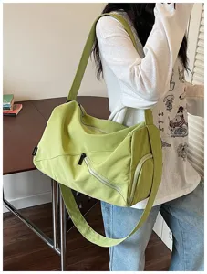 Détail de sac de voyage bandoulière décontracté vert montrant poche zippée et tissu.