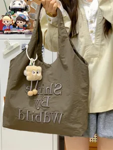 Slouchy nylon canvas tote bag detail view, casual lightweight shoulder bag with plush charm.