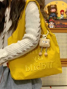 Detail shot of the stylish yellow canvas tote bag showing its unique embroidered letter design and soft texture.