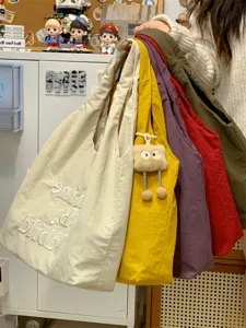 Casual canvas tote bag in multiple colors with cute plush pendant for daily commute and shopping.