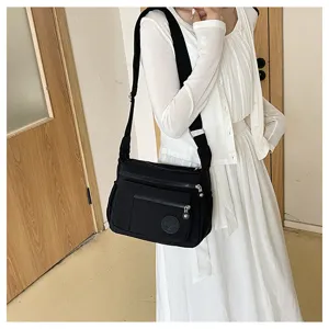 Black multi-pocket canvas shoulder bag for women, casual nylon crossbody travel handbag.