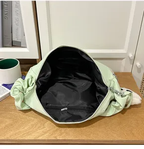 Green pleated cloud shoulder bag detail showing black inner lining, zipper and spacious interior.