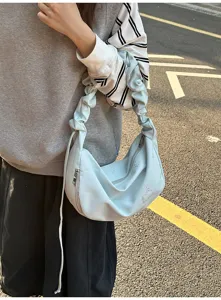 Close-up of stylish light blue cloud shoulder bag with cute bow embroidery and gathered strap.