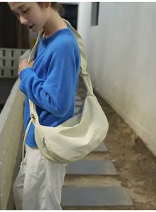 Detail view of cream canvas crescent shoulder bag featuring cute bow embroidery for daily wear.