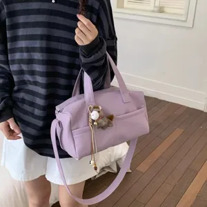 Close-up view of stylish purple casual tote shoulder bag featuring cute pony plush pendant.
