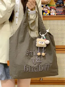 Casual canvas tote bag for women, lightweight daily commuting shoulder bag with cute plush pendant.
