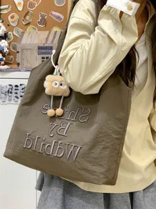 Detail view of casual canvas tote bag with cute plush pendant and stylish embroidery design.