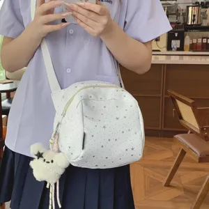 Close up detail view of white star print crossbody bag featuring cute plush bear charm.