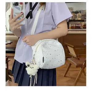Close-up detail of the white star-patterned crossbody bag featuring a cute plush bear charm.