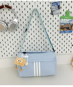 Casual large-capacity light blue canvas crossbody bag with cute plush charm and sports stripes.