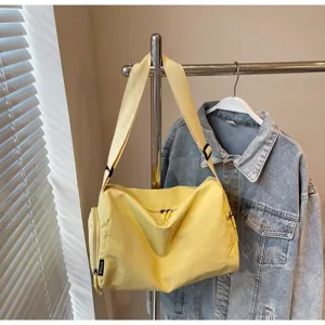 Detail shot of a casual yellow canvas duffel bag hanging on a rack with adjustable strap.