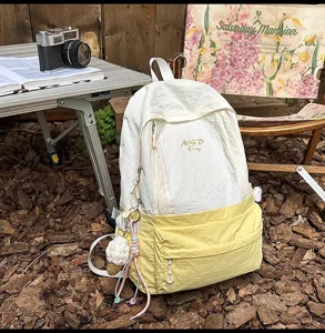 Lightweight nylon colorblock backpack with front pocket and cute charm for outdoor daily use.