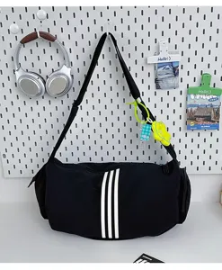 Detailansicht der schwarzen Reisetasche mit drei Streifen Design und lässiger Schultertasche.
