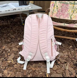 Pink outdoor lightweight backpack detail showcasing pleated fabric and side zipper pocket.
