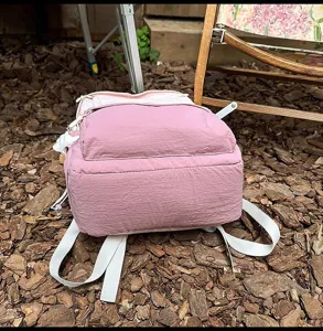 Closeup detail of pink casual backpack outdoor scene showing straps and pocket design.