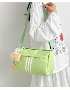 Detailed view of light green cylindrical crossbody bag with three stripes and plush charm.