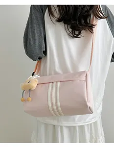 Pink cylindrical crossbody bag detail shot, daily casual shoulder bag with cute plush pendant.