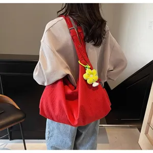 Détail du sac bandoulière rouge en toile style décontracté avec joli pendentif fleur jaune.