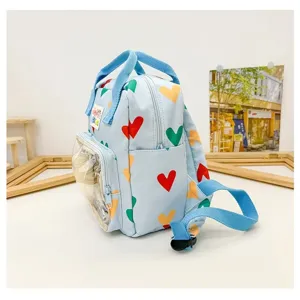 Cute light blue kids mini backpack featuring colorful heart prints and clear front pocket detail.
