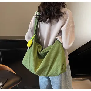Vue détaillée d'un grand sac bandoulière en toile verte, montrant la texture et la bandoulière.