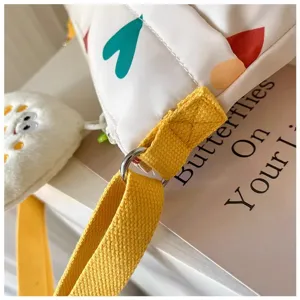 Detail view of women canvas crossbody shoulder bag strap and cute pendant accessory.