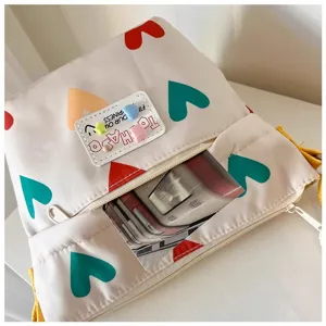 Close-up detail of canvas crossbody bag showcasing colorful heart prints and zipper pocket.