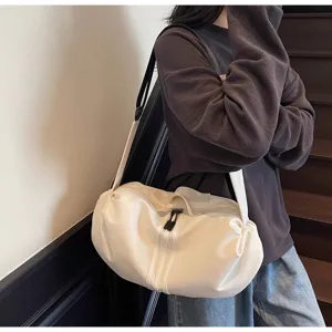 Close-up view of the casual white crossbody shoulder bag worn by a model indoors, showing detail and style.