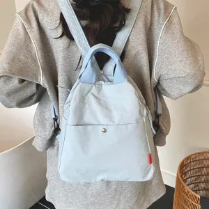 Light blue canvas casual backpack detail view showing dual handles and front pocket design