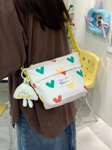 Cute canvas crossbody bag for women, summer heart print shoulder bag with plush pendant.