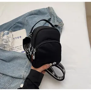 Pequeño bolso cruzado de nailon negro con asa superior y correa estampada de diseño elegante.