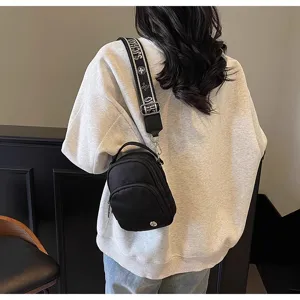 Bolso bandolera negro informal para mujer con correa estampada y diseño de múltiples bolsillos.