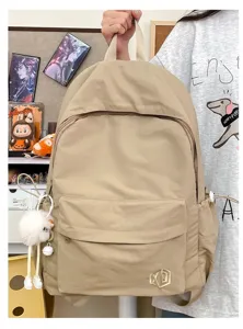 Solid color casual backpack for daily use, featuring front zip pocket and cute plush charm.
